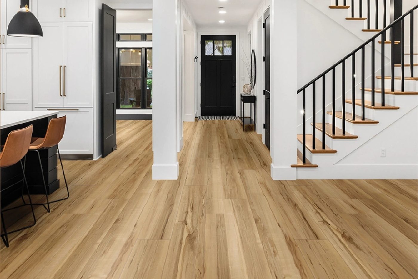 Wide plank luxury vinyl flooring running through an open hallway into a kitchen