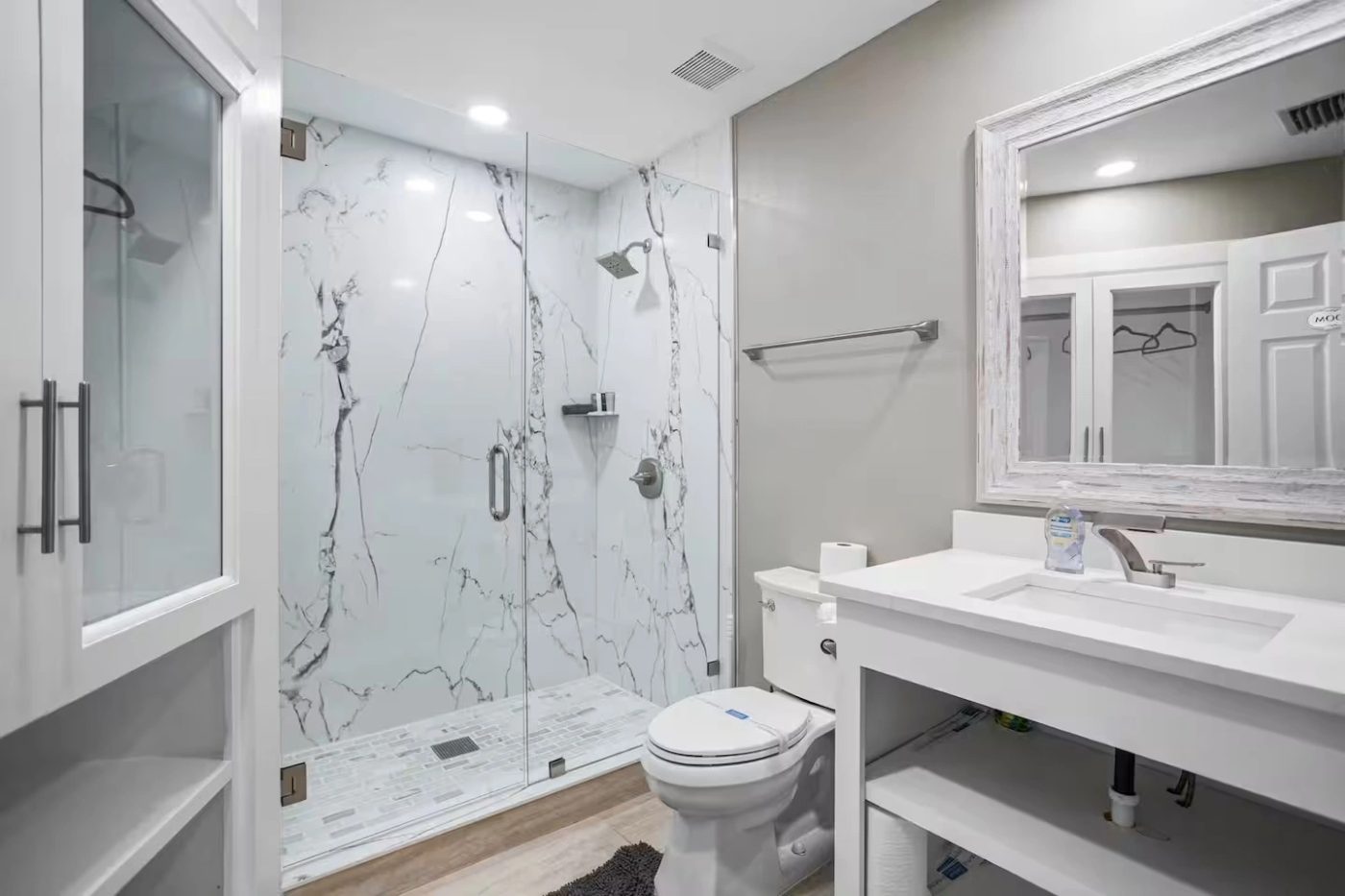 Bathroom with a full height marble effect shower surround, glass screen and a white quartz vanity top