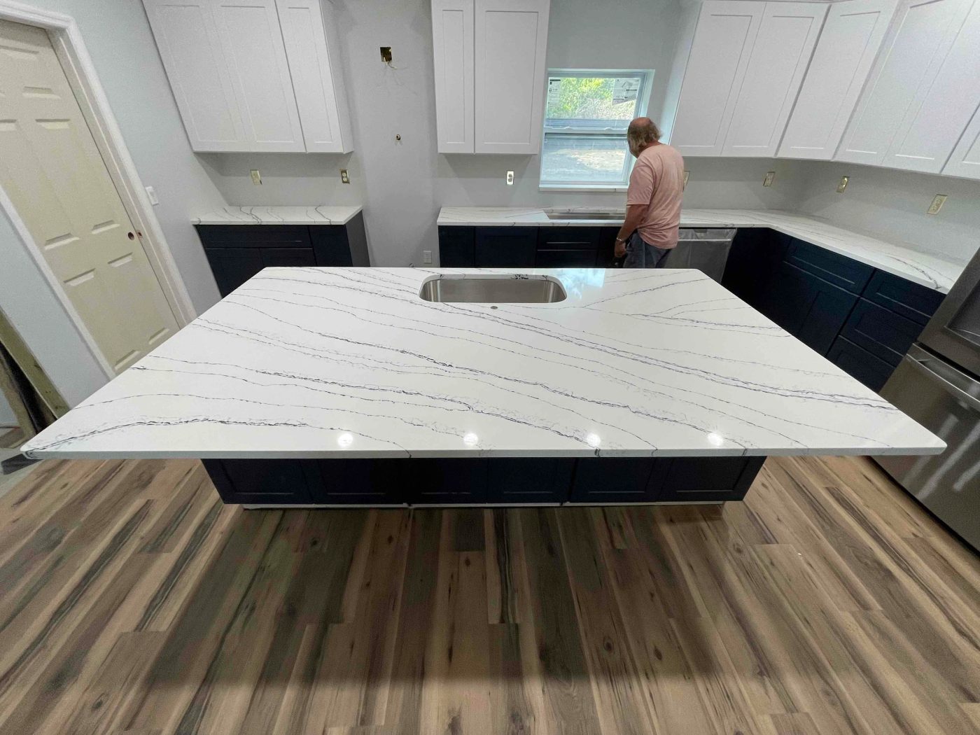 A large white quartz island being installed over navy shaker cabinets